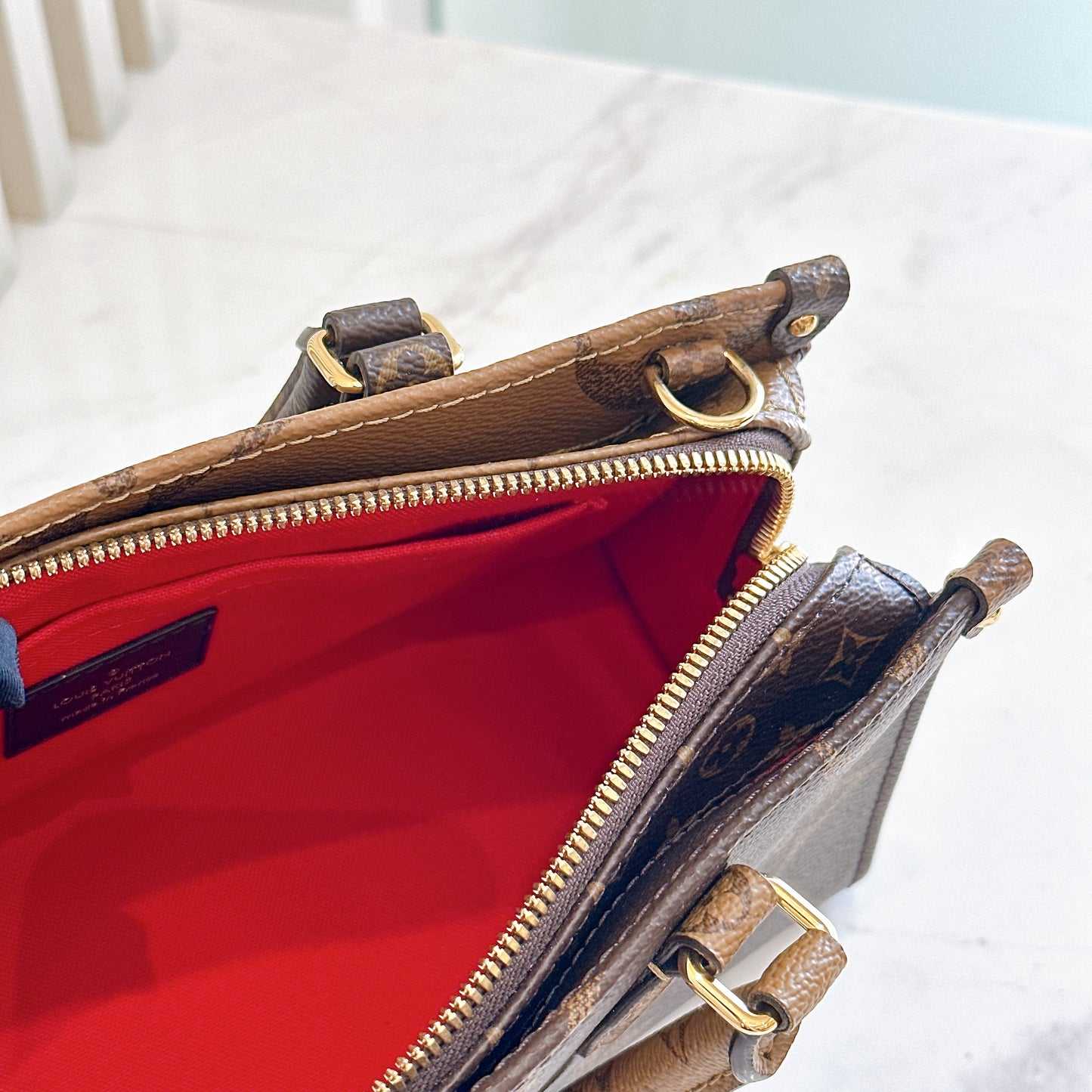 LV On The Go East West in Monogram Reverse